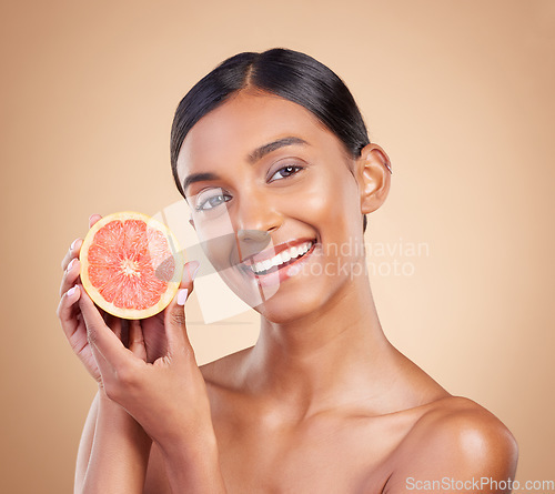 Image of Portrait, skincare and grapefruit with a model woman in studio on a beige background to promote beauty. Face, fruit and natural with an attractive young female posing for organic or luxury cosmetics