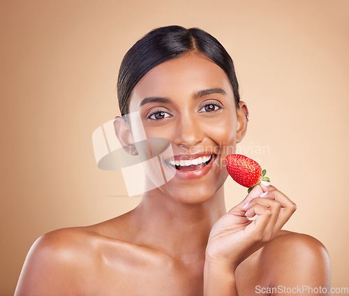 Image of Portrait, skincare and strawberry with a model woman in studio on a beige background to promote beauty. Face, fruit and nutrition with an attractive female posing for organic or natural cosmetics