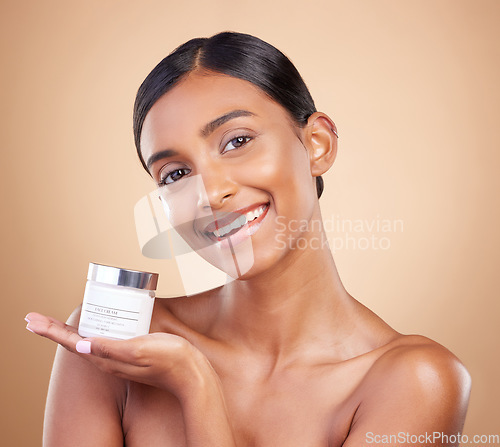 Image of Portrait, product and lotion with a model woman in studio on a beige background for beauty or skincare. Face, advertising and moisturizer with an attractive young female holding a cosmetics container