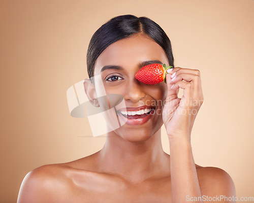 Image of Portrait, beauty and strawberry with a model woman in studio on a beige background to promote skincare. Face, eye and fruit with an attractive young female posing for organic or natural cosmetics