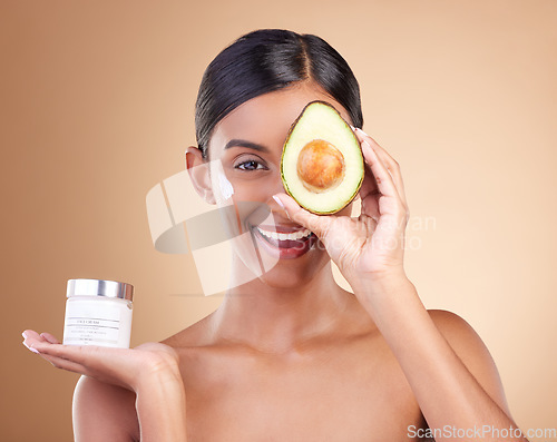 Image of Skincare, avocado and cream with portrait of Indian woman in studio for product, cosmetics and beauty. Self care, glow and natural with model and lotion for facial, spa and youth on brown background