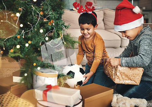 Image of Festive, happy and children with christmas gifts opening boxes by the tree for celebration. Happiness, holiday and kid siblings with presents in the living room to celebrate xmas at their family home