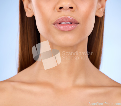 Image of Lips, shine and beauty with face and woman in closeup for cosmetic care and lipstick on blue background. Skin glow, dermatology and skincare, female with lip filler and facial with makeup in studio