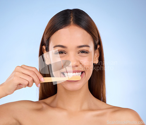 Image of Portrait, toothbrush and smile with a model woman in studio on a blue background for oral hygiene. Mouth, cleaning and dental with an attractive young female brushing her teeth for whitening