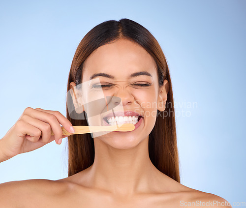 Image of Toothbrush, toothpaste and cleaning with a woman in studio on a blue background for oral hygiene. Mouth, dentist and dental with an attractive young female brushing her teeth for healthy gums