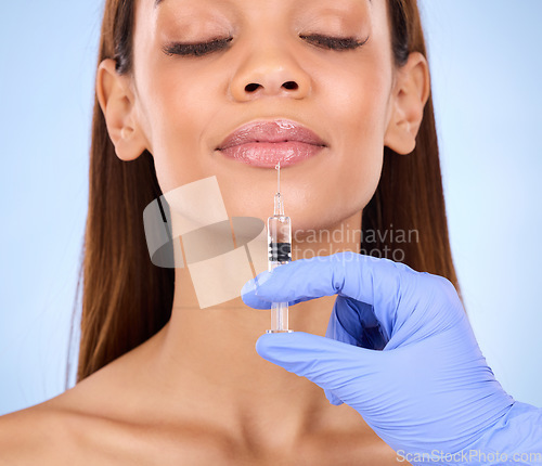 Image of Face, lips and injection of woman on studio, blue background and facial cosmetics. Young female model, lip filler and needle for plastic surgery, skincare transformation and aesthetic mouth change