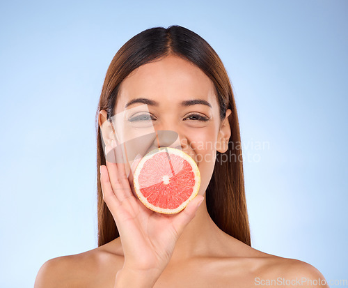 Image of Grapefruit, woman and beauty face portrait for skincare dermatology and vitamin c. Female model on a blue background for self care, facial glow and healthy fruit for natural and clean skin in studio