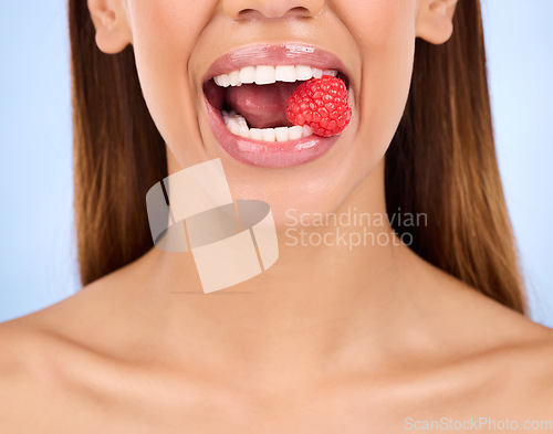 Image of Woman, mouth and raspberry for skincare nutrition, dermatology or diet health plan against a studio background. Female lips with fruit for natural organic food, self care or eat for healthy wellness