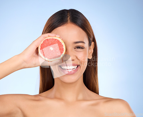 Image of Beauty, grapefruit and woman for face portrait with a smile for skincare dermatology and vitamin c. Model on blue background for self care, facial glow and healthy fruit for natural skin in studio