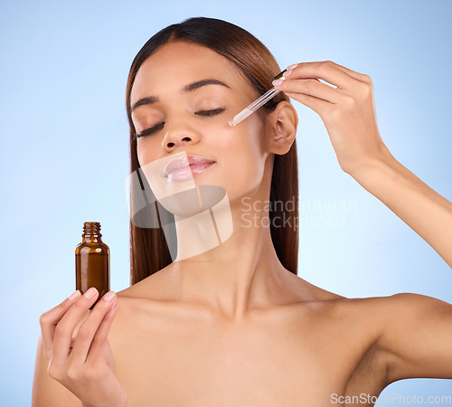 Image of Beauty, skincare and cosmetics, hispanic woman with serum in pipette for anti aging skin glow on blue background. Makeup, facial repair and face of model with solution or collagen product in studio.