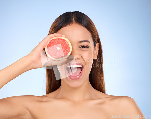 Image of Beauty, excited woman and grapefruit portrait for skincare cosmetic and vitamin c. Female model on blue background for self care, facial glow or healthy fruit on natural skin and happy face in studio