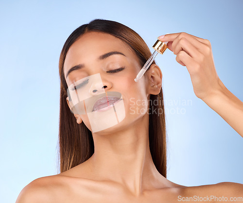 Image of Skincare, beauty and hispanic woman with serum in pipette for anti aging or skin glow on blue background. Cosmetics, facial repair and face of model with solution or collagen product in studio promo.