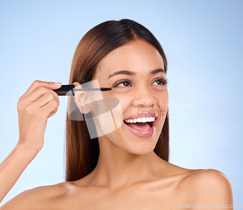 Image of Beauty, mascara makeup and woman with cosmetics on face in studio. Excited female model person on a blue background for self care, facial glow and eyelash extension or growth with luxury product