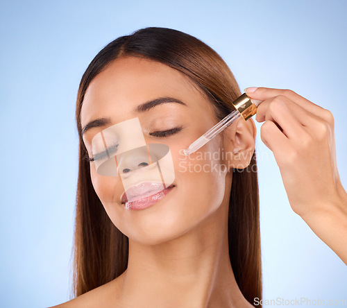 Image of Skincare, cosmetics and hispanic woman with serum in pipette for anti aging or skin glow on blue background. Beauty, facial repair and face of model with solution or collagen product in studio promo.