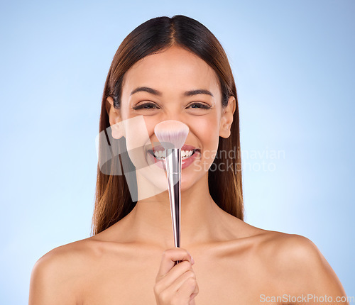 Image of Beauty, makeup and brush on nose of woman in studio for cosmetics, satisfaction and self care. Glow, foundation and blush with girl model on blue background for facial, powder and cosmetology product