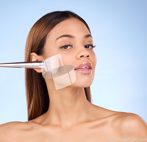 Image of Beauty, makeup brush and blush with woman in studio for cosmetics, tools and self care. Glow, foundation and face with girl model on blue background for facial, powder and cosmetology product