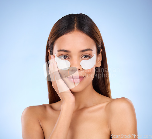 Image of Skincare, eyes and portrait of woman with collagen eye mask for anti aging skin on blue background. Cosmetics, facial repair and face of beauty model with wrinkle treatment product in studio.