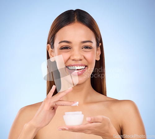 Image of Woman, portrait and face with moisturizer creme for beauty skincare cosmetics, self love or care against a blue studio background. Happy female with lotion or moisturizing cream for soft perfect skin