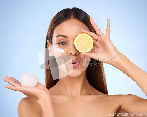Image of Woman, moisturizer cream and lemon for natural skincare, beauty and vitamin C against blue studio background. Portrait of female holding citrus fruit, creme or lotion for healthy organic nutrition