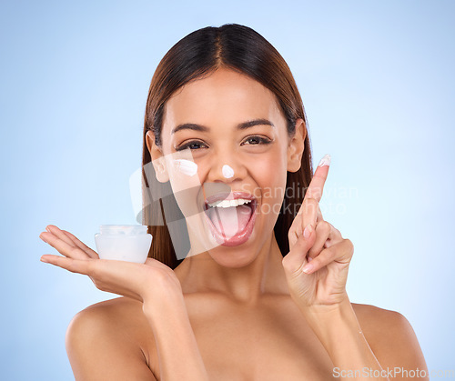 Image of Skincare portrait of excited woman, cream on finger and anti aging skin care on blue background. Cosmetics, facial and face of hispanic model with moisturizer solution or collagen product in studio.