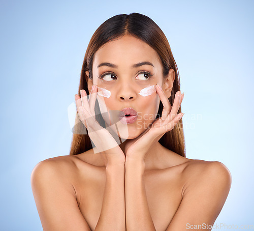 Image of Skincare, beauty and dermatology, woman with eye cream and anti aging skin care wow on blue background. Cosmetics, facial repair and surprise, face of hispanic model with product in studio promo.