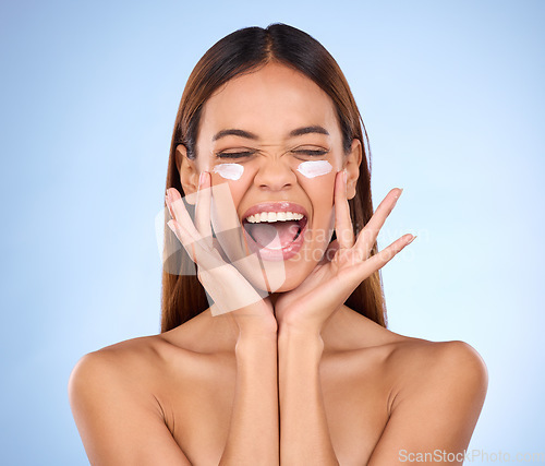 Image of Dermatology, portrait of excited woman with cream on face and anti aging skin care on blue background. Cosmetics, facial and happy hispanic model, moisturizer solution or collagen product in studio.