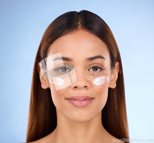 Image of Skincare, dermatology and portrait of woman with eye cream for anti aging skin care glow on blue background. Cosmetics, clean facial or face of hispanic beauty model with product in studio promotion.