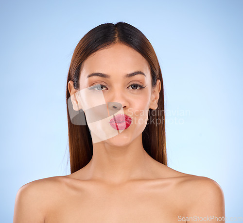 Image of Woman, beauty and red lipstick makeup portrait with cosmetics on face in studio. Aesthetic female model on a blue background for self care, facial glow and shine or color for lips and skin wellness