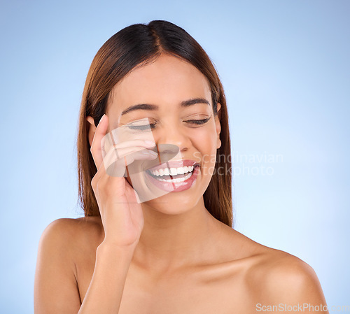 Image of Skincare, beauty and happy woman with smile in studio for skin glow promo with hand on face on blue background. Makeup, facial and cosmetics, African model for dermatology or spa promotion and mockup