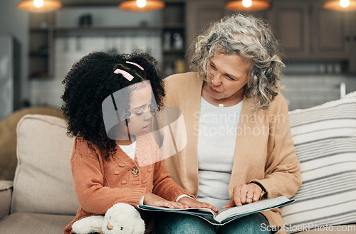 Image of Family kid, book and grandmother reading fantasy storybook, story or bonding on home living room sofa. Love, grandma babysitting and senior woman with child development for adoption kindergarten girl