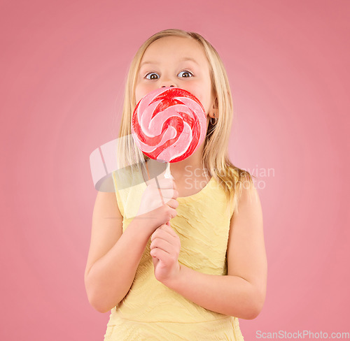 Image of Candy, sugar rush and lollipop with girl in studio for sweets, party and carnival food isolated on pink background. Cute, excited and youth with child and eating colorful snack for playful and treat