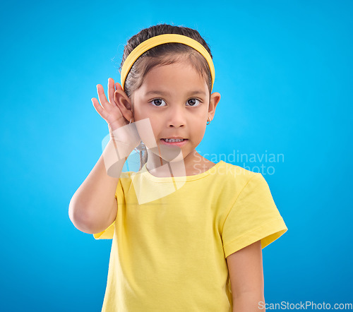 Image of Hearing, eavesdrop and portrait of a children listening isolated on a blue background in a studio. Listen, attention and young girl holding an ear for sound, gossip and a secret on a backdrop