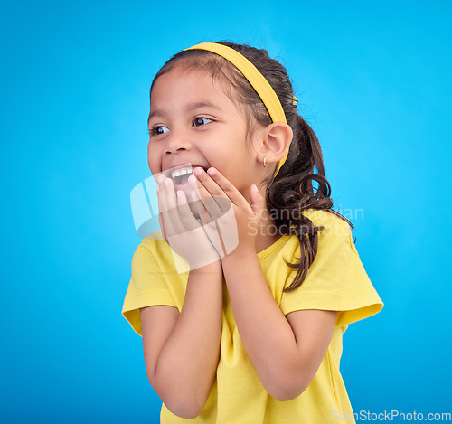 Image of Laughing, happy and child looking curious while isolated on a blue background in a studio. Smile, cheerful and an adorable little girl with a laugh, happiness and innocent delight on a backdrop