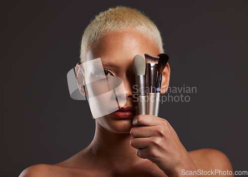 Image of Woman, portrait and makeup brushes for facial beauty cosmetics, skincare or treatment against a gray studio background. Beautiful female holding cosmetic brushing tools on face for self care or love