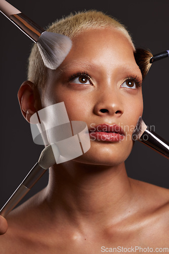 Image of Woman, face and beauty with makeup brushes for skincare cosmetics or treatment against a gray studio background. Beautiful female model with cosmetic brushing tools for facial, self care or love