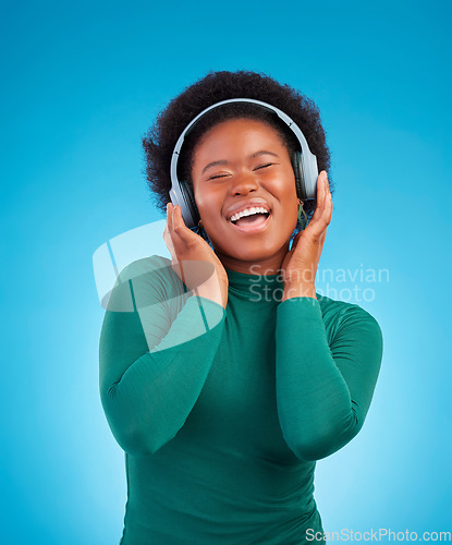 Image of Happy, music and headphones with black woman in studio for streaming, singing and relax. Online radio, technology and listening with female isolated on blue background for hip hop and subscription