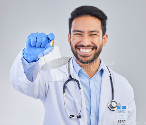 Image of Happy, portrait and doctor with pill in studio, smile for medicine, vitamin or cure on grey background. Medical, innovation and face of male healthcare expert with futuristic health supplement