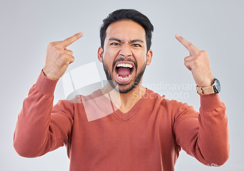 Image of Angry, middle finger and portrait of asian man in studio for rude, conflict and problem. Annoyed, upset and aggressive with male and hand gesture on gray background for hate, disrespect and furious