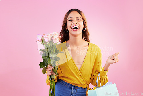 Image of Happy, shopping bags and flowers with woman in studio for retail, birthday and spring. Event, party and celebration with female customer and roses on pink background for sale, discount and romance