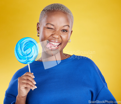 Image of Portrait, funny and black woman with lollipop, candy and happiness against a studio background. Face, African American female and lady with sweets, dessert and treats with silly, goofy and cheerful