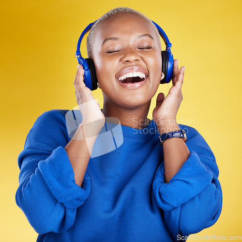 Image of Music, headphones and black woman singing in studio isolated on a yellow background. Podcast, radio singer and happy African female streaming, enjoying and listening to audio, sound track or song.