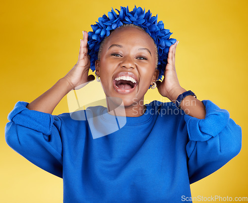 Image of Portrait, queen and flower crown with an excited black woman in studio on a yellow background. Face, expression and sustainability with an attractive female wearing a blue wreath as royalty