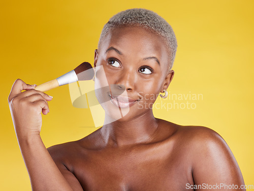Image of Face, makeup and beauty of black woman with brush in studio isolated on a yellow background. Thinking, cosmetics and happy African female model with tool to apply foundation or powder for facial skin
