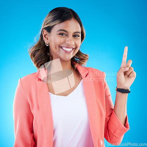 Image of Smile, portrait and Indian woman in studio pointing up for product placement, mockup or information. Deal, promotion or announcement, happy model showing info space or notification on blue background