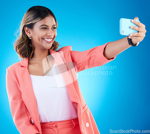 Image of Selfie, smile and business woman in studio isolated on a blue background. Photographer, professional and Indian female entrepreneur taking photo for happy memory, social media and profile picture.