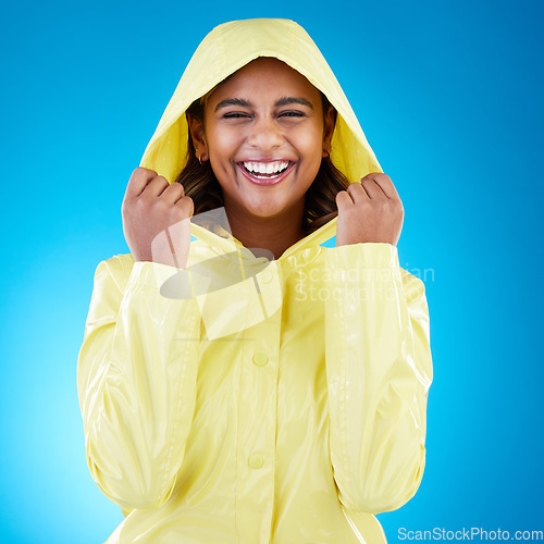 Image of Cover, happy and portrait of a woman with a raincoat isolated on a blue background in a studio. Smile, laughing and girl wearing a jacket to protect from rain, the cold or bad weather on a backdrop