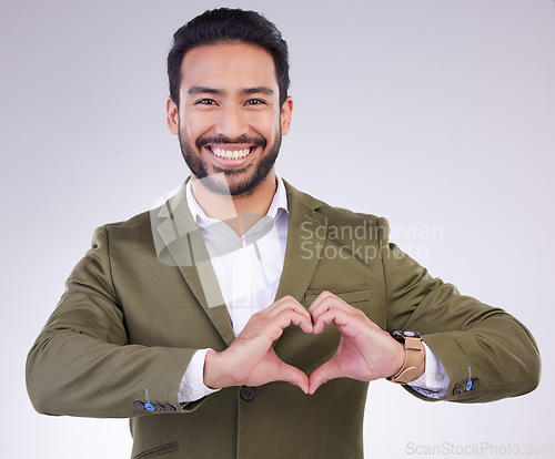 Image of Hands, heart shape and business man portrait in studio for support, love and charity on a gray background. Asian entrepreneur person with hand emoji or icon for care, motivation and kindness smile
