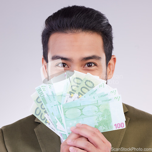 Image of Portrait, cash and euro with a business man in studio holding money on a gray background for finance. Smile, accounting or investment with a happy male employee proud of his financial trading success