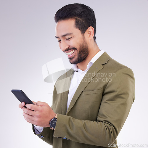 Image of Business man, smile and phone for communication in studio while typing and networking on gray background. Asian male entrepreneur with smartphone for email, online chat or marketing on social media