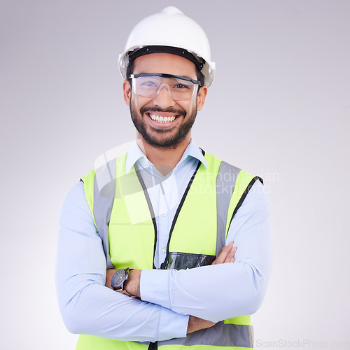 Image of Construction worker in portrait, man with crossed arms and smile, architect or engineer in building industry on studio background. Happy contractor, professional builder with helmet and goggles